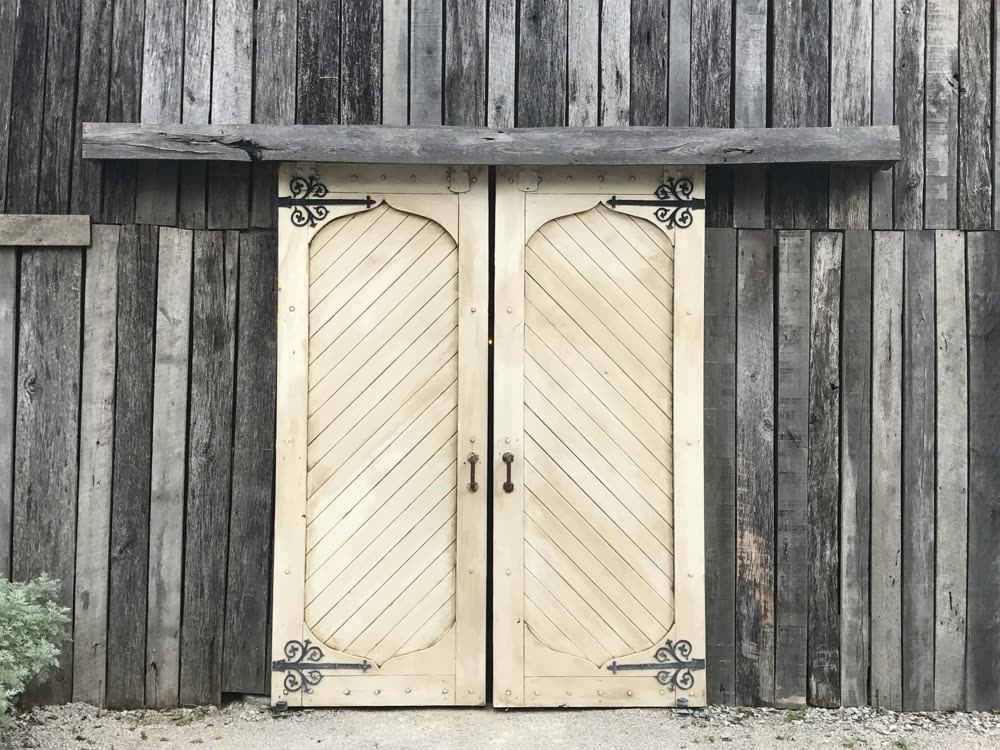 Weathered plank barn doors with iron strap hinges